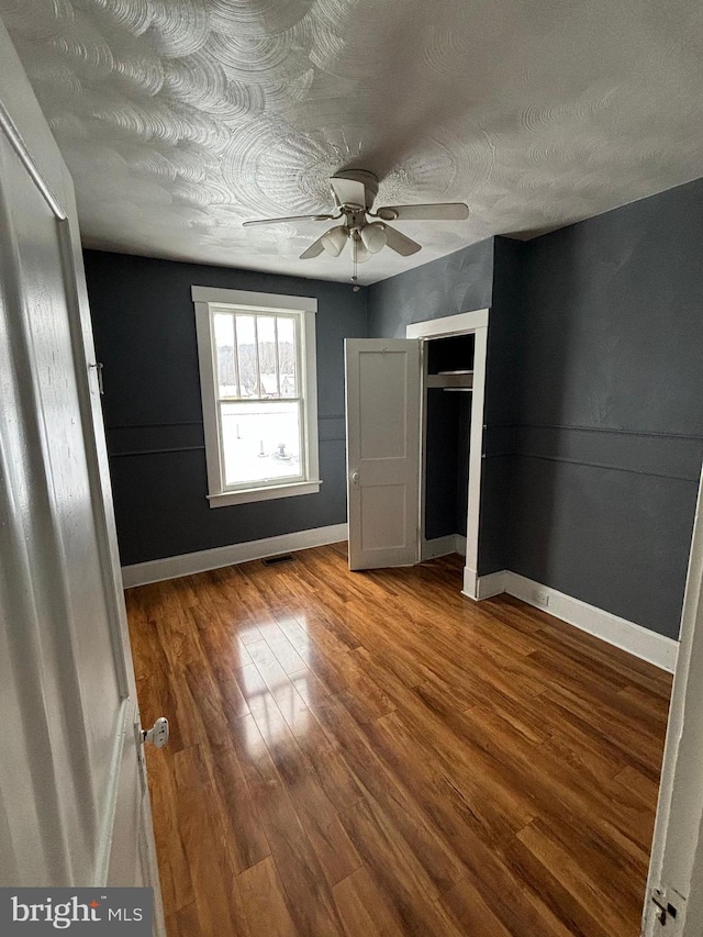 unfurnished bedroom featuring a textured ceiling, hardwood / wood-style flooring, and ceiling fan