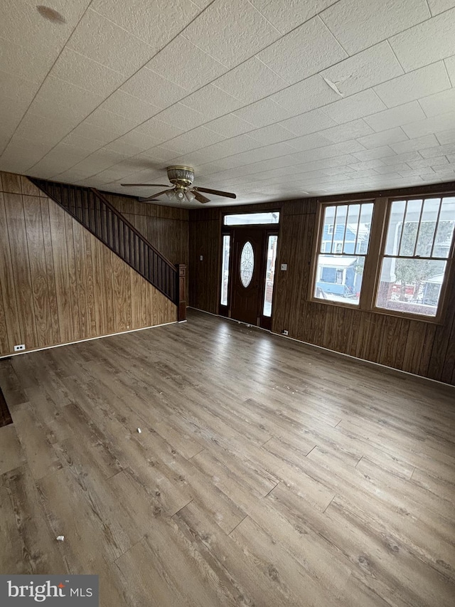 entryway featuring hardwood / wood-style flooring, ceiling fan, and wood walls