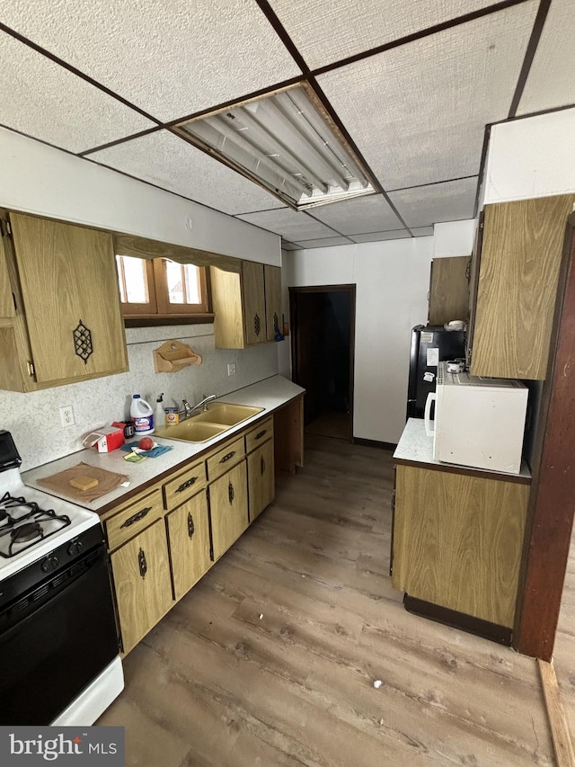 kitchen with backsplash, a drop ceiling, sink, hardwood / wood-style flooring, and white gas stove