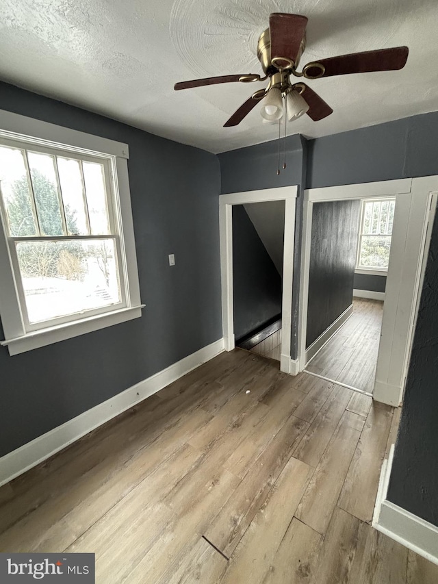 unfurnished room featuring a textured ceiling, light hardwood / wood-style floors, and ceiling fan