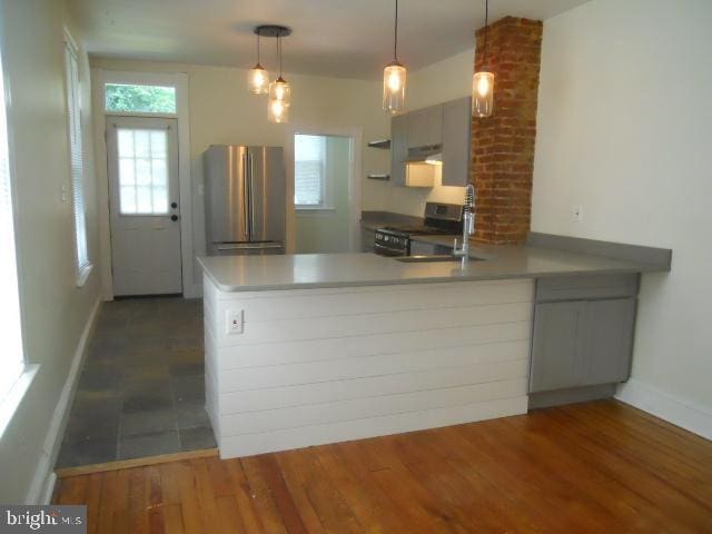 kitchen featuring pendant lighting, kitchen peninsula, stainless steel appliances, and dark wood-type flooring