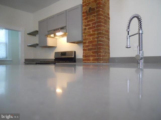 kitchen featuring range, gray cabinetry, and range hood