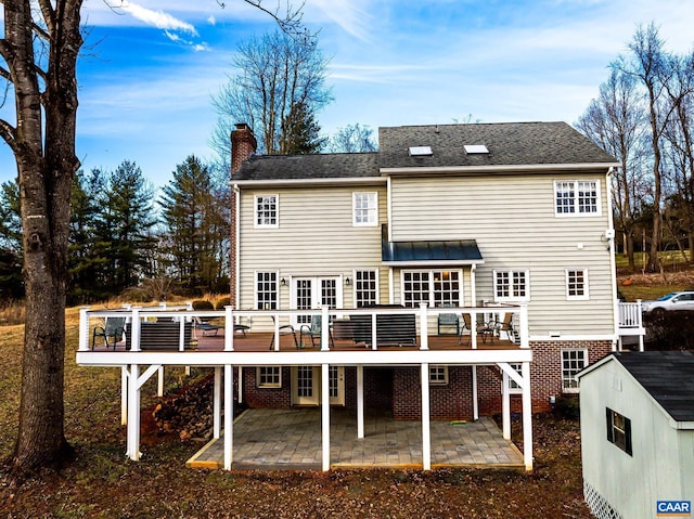 back of house featuring a wooden deck, a patio area, and a shed