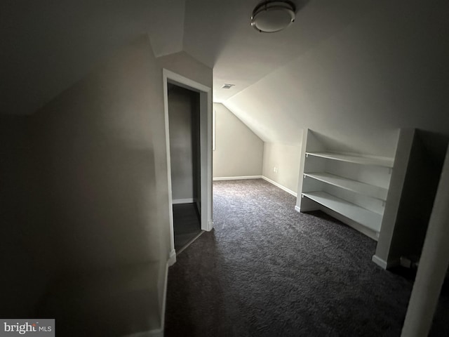 additional living space featuring dark carpet and lofted ceiling