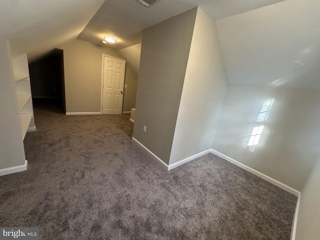 additional living space with dark carpet and vaulted ceiling