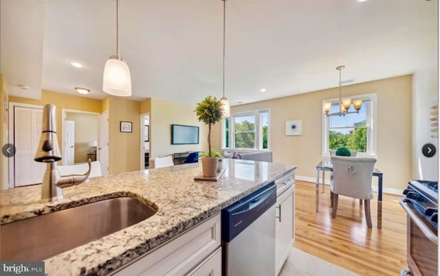 kitchen with sink, hanging light fixtures, white cabinetry, stainless steel appliances, and a chandelier