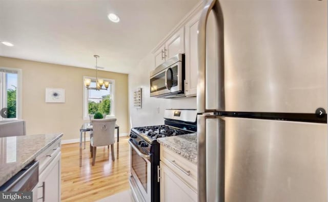 kitchen featuring light stone countertops, white cabinetry, a chandelier, and appliances with stainless steel finishes