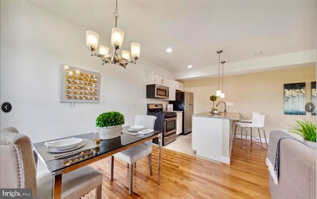 dining area featuring sink, a chandelier, and light wood-type flooring