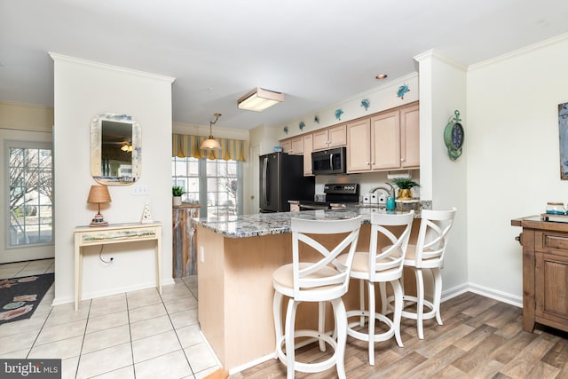 kitchen featuring crown molding, electric range oven, a kitchen breakfast bar, light stone counters, and black fridge