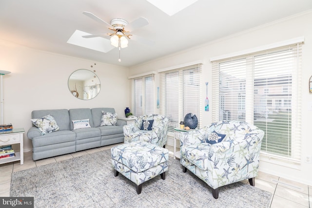 living room featuring ceiling fan, ornamental molding, tile patterned floors, and a skylight