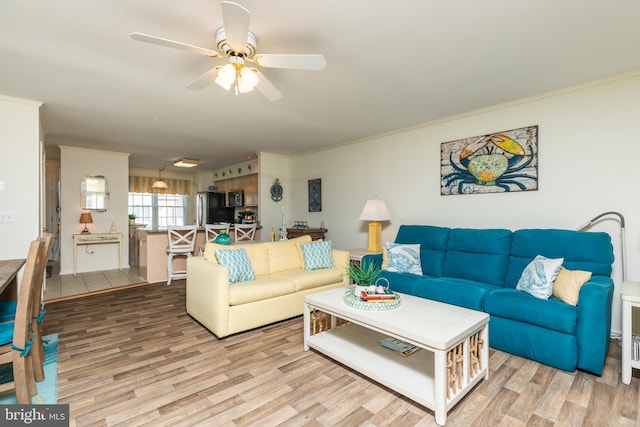 living room with crown molding, light hardwood / wood-style floors, and ceiling fan