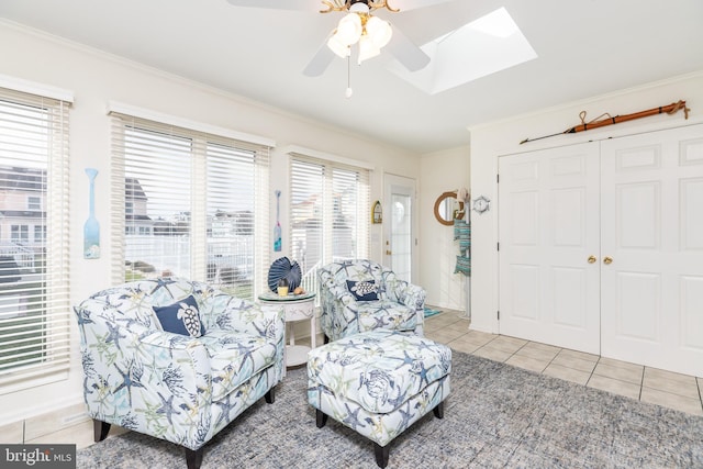 living area with crown molding, a skylight, tile patterned floors, and ceiling fan