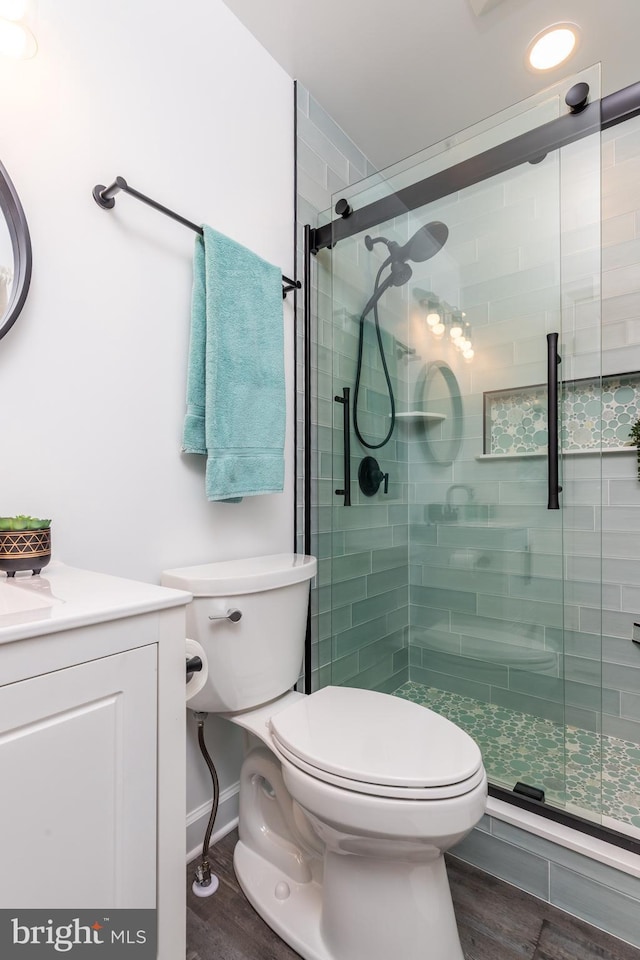 bathroom featuring hardwood / wood-style flooring, vanity, toilet, and a shower with shower door