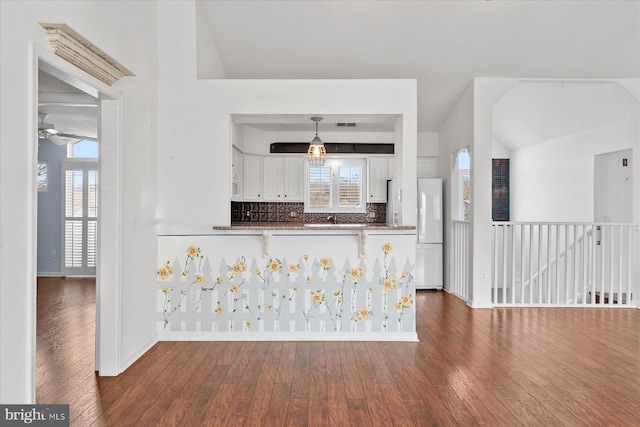 kitchen featuring decorative backsplash, white fridge, white cabinetry, and lofted ceiling