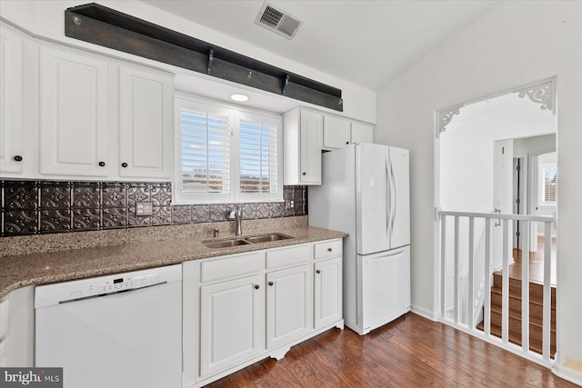 kitchen featuring white appliances, stone counters, sink, vaulted ceiling, and white cabinetry