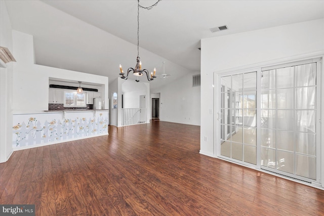 unfurnished living room with hardwood / wood-style floors, a chandelier, and vaulted ceiling