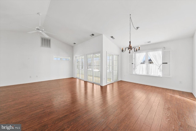 empty room with ceiling fan with notable chandelier, hardwood / wood-style flooring, and vaulted ceiling