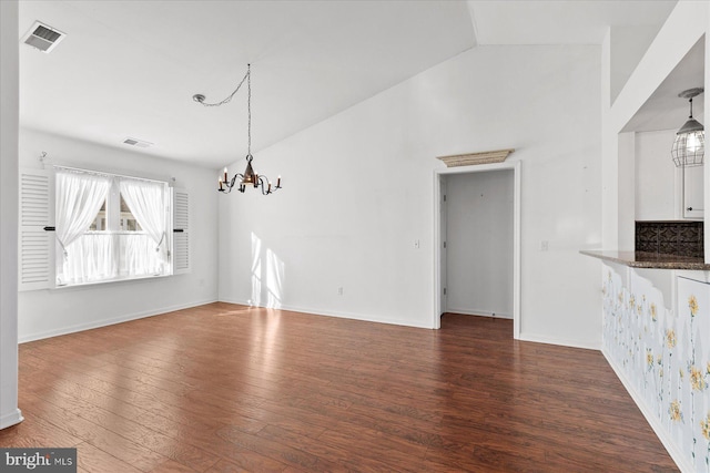 unfurnished dining area with dark hardwood / wood-style flooring, lofted ceiling, and an inviting chandelier