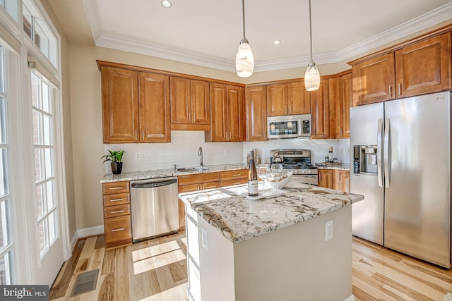 kitchen featuring sink, a center island, light stone counters, light hardwood / wood-style floors, and appliances with stainless steel finishes