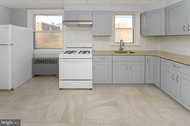 kitchen featuring white appliances, radiator, gray cabinets, under cabinet range hood, and a sink