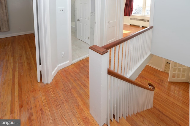 stairs with baseboards, radiator heating unit, and wood finished floors