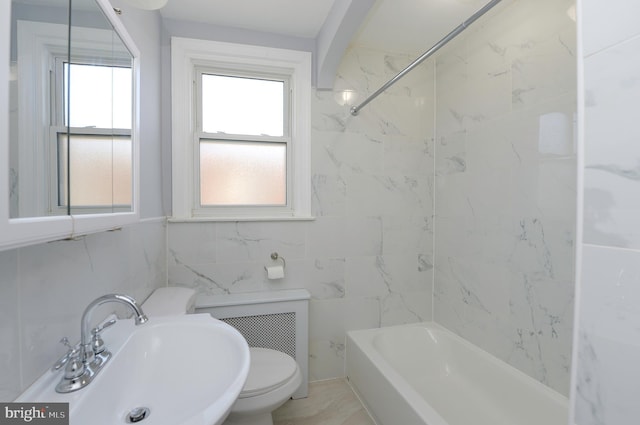 bathroom with shower / tub combination, a sink, toilet, and tile walls