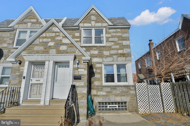 townhome / multi-family property featuring stone siding and fence