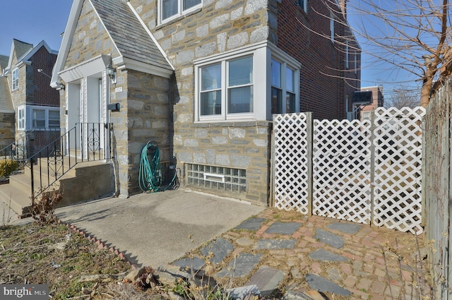 view of side of home featuring stone siding and a patio area