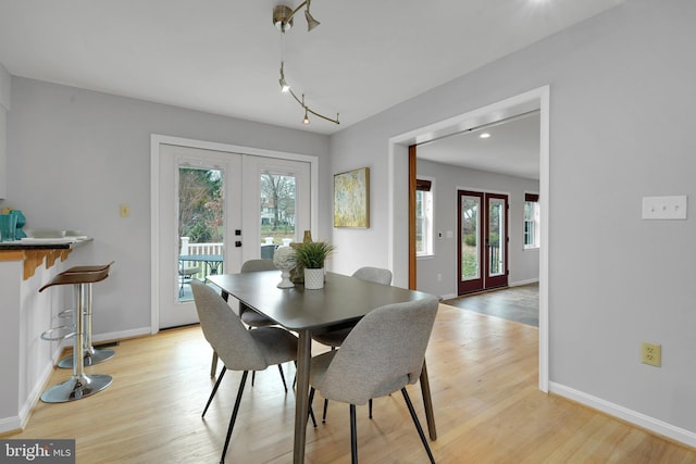 dining area with light wood-type flooring and french doors