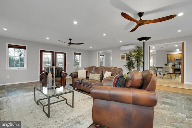 living room featuring an AC wall unit, plenty of natural light, and ceiling fan