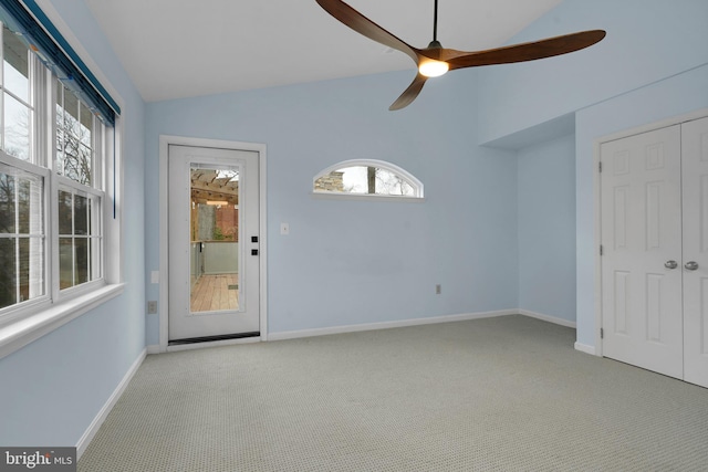 unfurnished room featuring ceiling fan, a healthy amount of sunlight, lofted ceiling, and light carpet