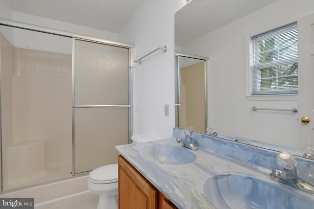 bathroom featuring vanity, toilet, and a shower with door