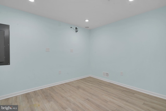 spare room with electric panel and light hardwood / wood-style floors