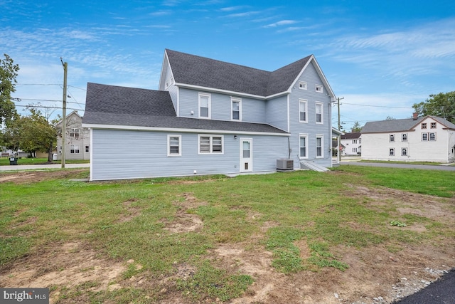 back of house with central AC unit and a yard