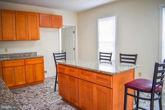 kitchen featuring light stone countertops, a center island, and a kitchen bar