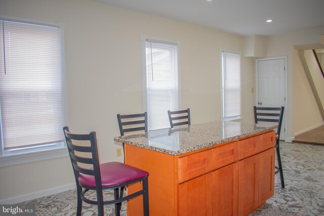 kitchen with light stone counters, a center island, and a breakfast bar area