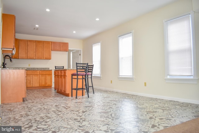 kitchen with light stone countertops, a center island, and a breakfast bar area