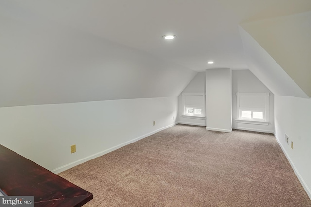 bonus room with lofted ceiling and light carpet