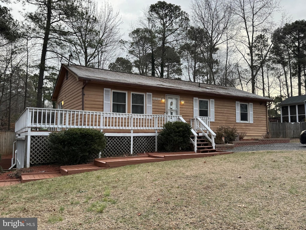 view of front of house with a wooden deck and a front lawn