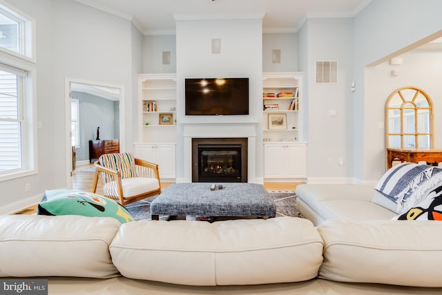 living room featuring a wealth of natural light, built in features, hardwood / wood-style floors, and ornamental molding