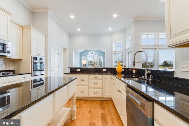 kitchen featuring sink, stainless steel appliances, dark stone counters, light hardwood / wood-style floors, and decorative backsplash