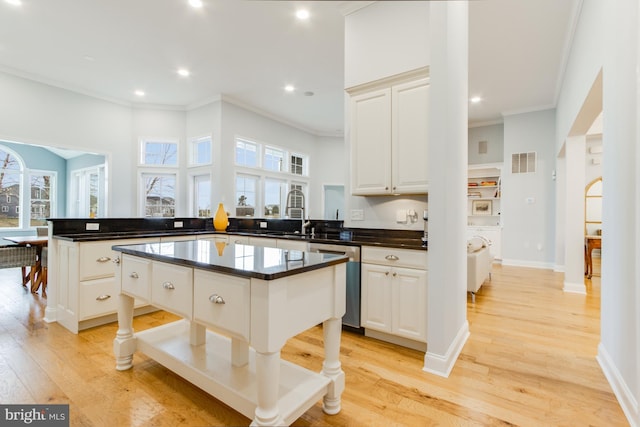 kitchen featuring a center island, white cabinets, stainless steel dishwasher, and light hardwood / wood-style floors