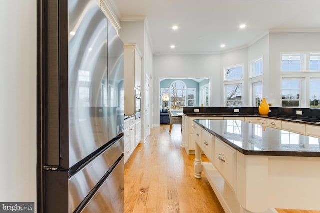 kitchen with stainless steel appliances, white cabinets, crown molding, a kitchen island, and light wood-type flooring