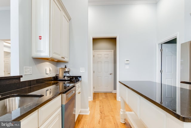 kitchen with stainless steel dishwasher, dark stone countertops, white cabinetry, and crown molding