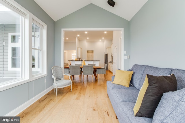 living room with a healthy amount of sunlight, light wood-type flooring, and lofted ceiling