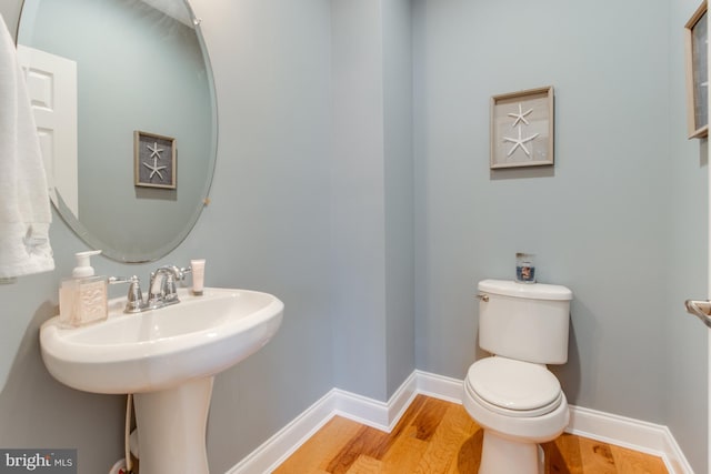 bathroom with hardwood / wood-style flooring, toilet, and sink