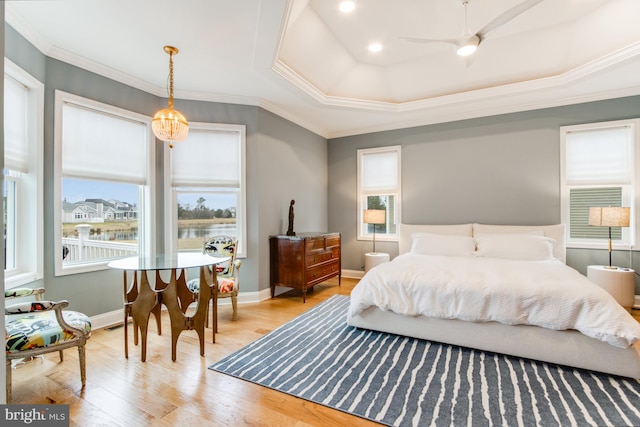 bedroom with ceiling fan, a raised ceiling, light wood-type flooring, and crown molding