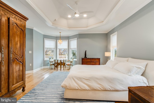 bedroom featuring a tray ceiling, ceiling fan, light wood-type flooring, and ornamental molding