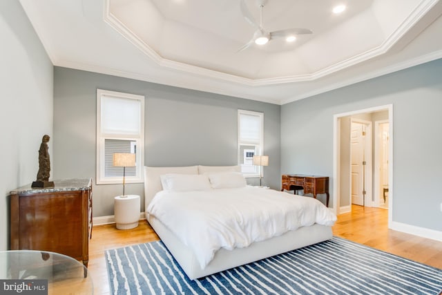 bedroom with light wood-type flooring, a tray ceiling, ceiling fan, and ornamental molding