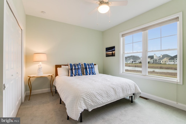 carpeted bedroom with ceiling fan and a closet